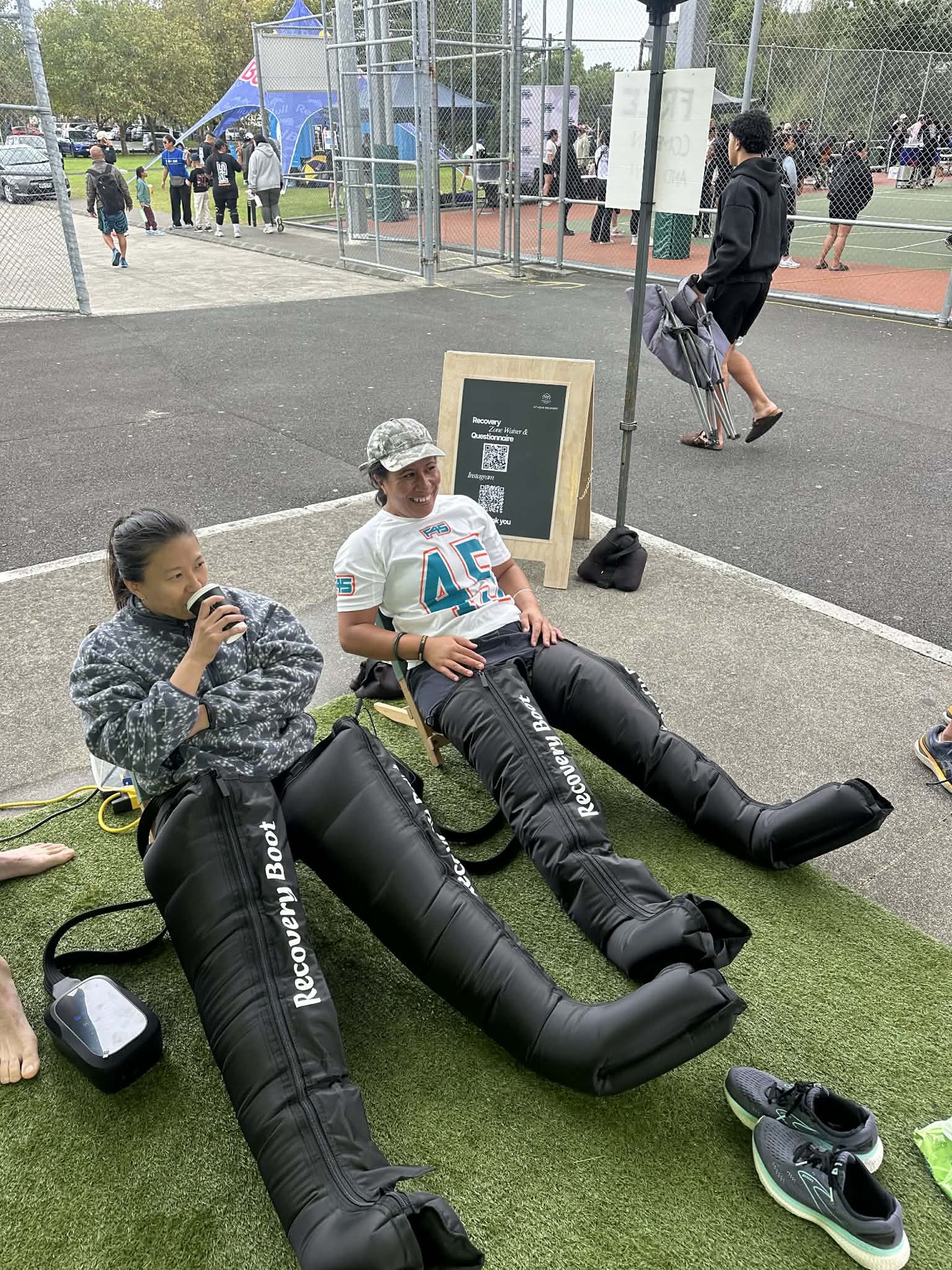 Two people relaxing in compression boots on turf