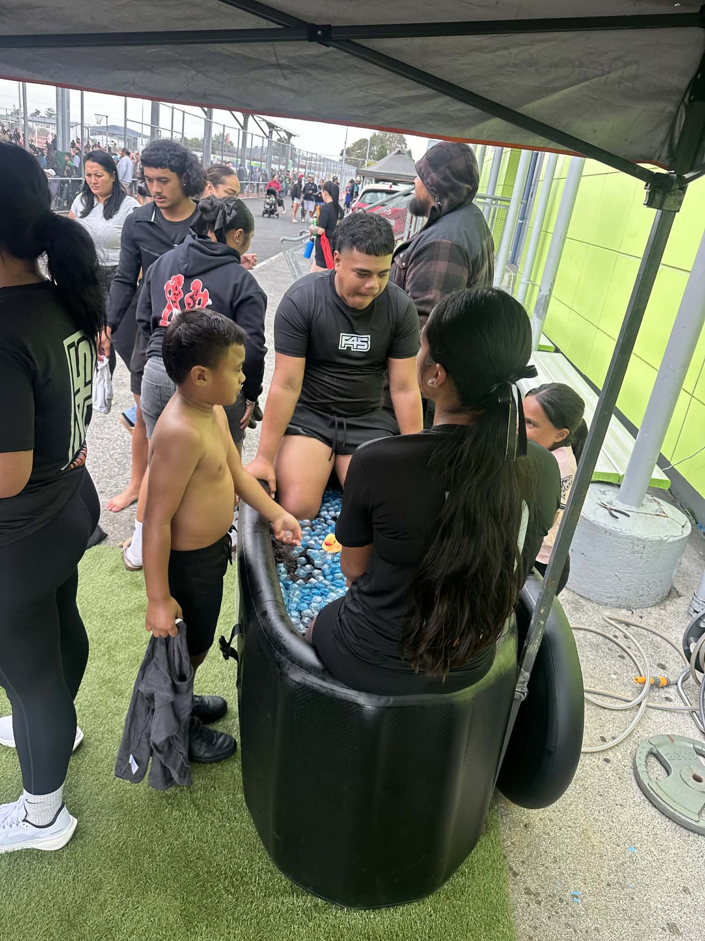 An athlete sitting in an ice bath at an event while the crowd watches