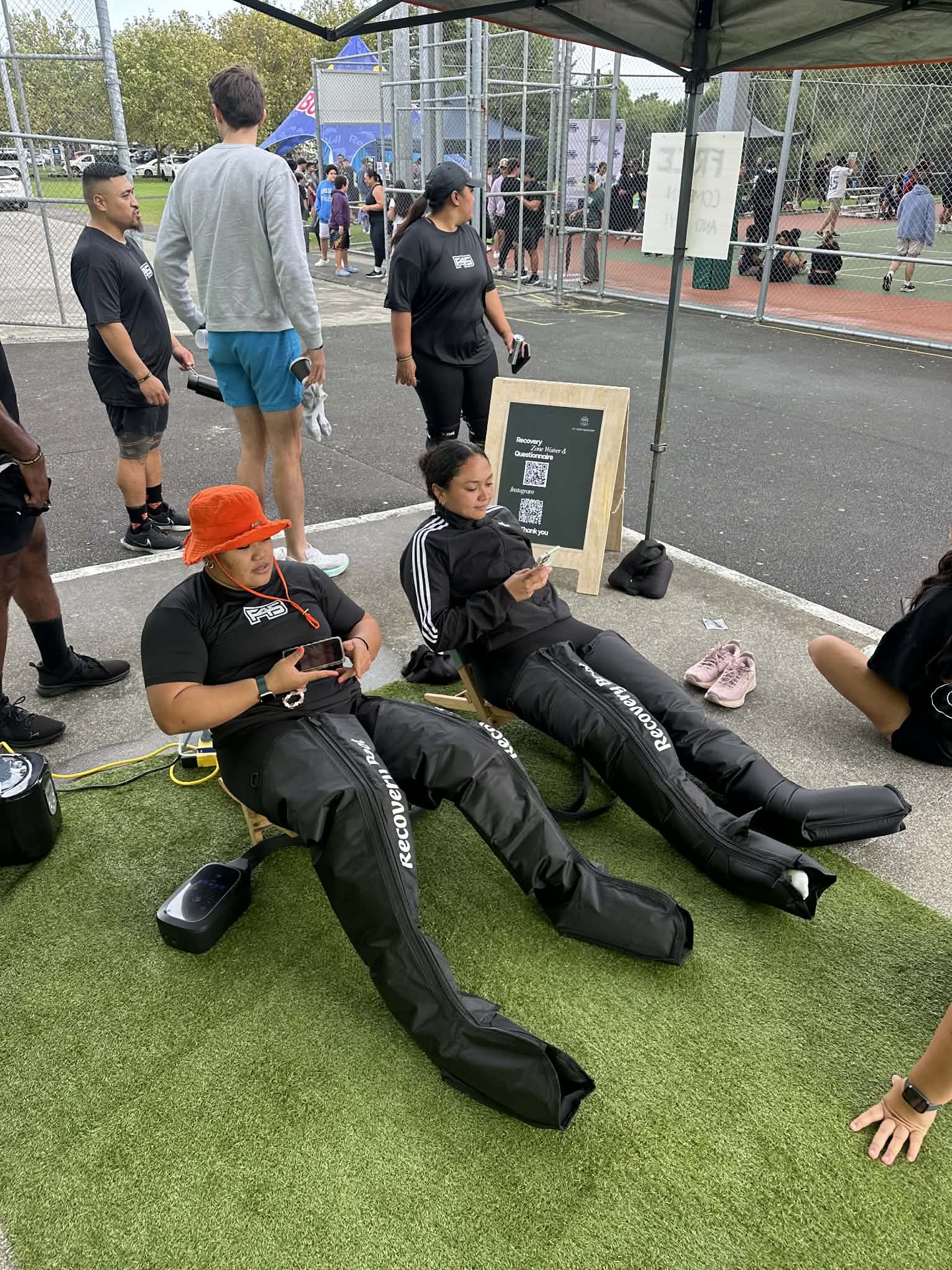Two athletes relaxing in compression boots at a pop-up