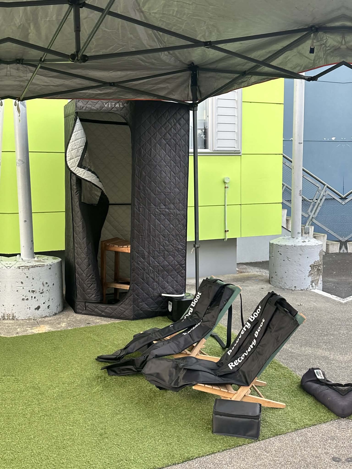 The sauna tent and compression boots set up on turf at an event